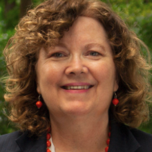 Woman with medium brown curly hair smiling